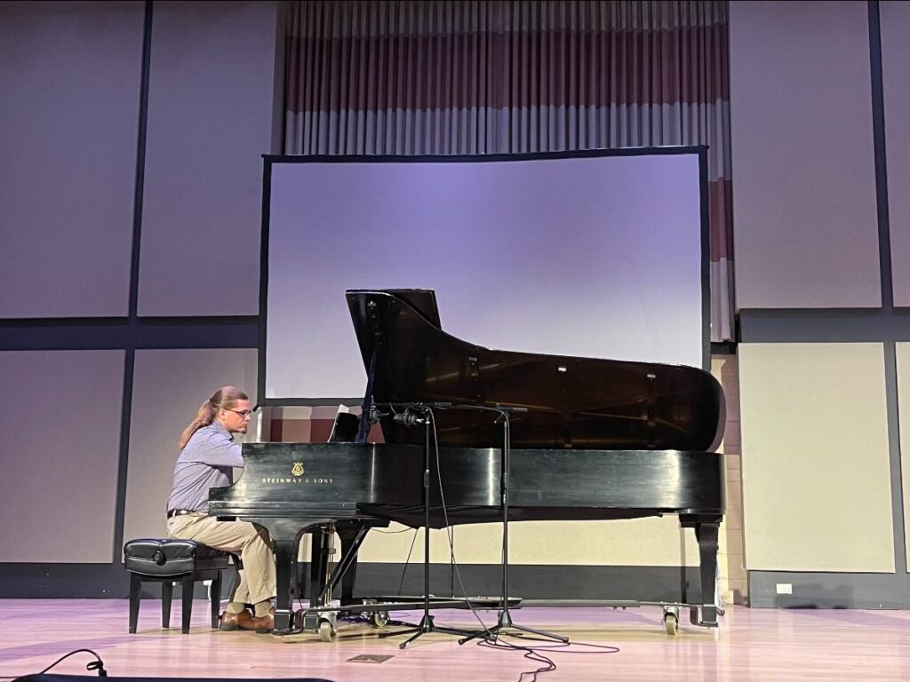 Man sitting at a grand piano on a stage