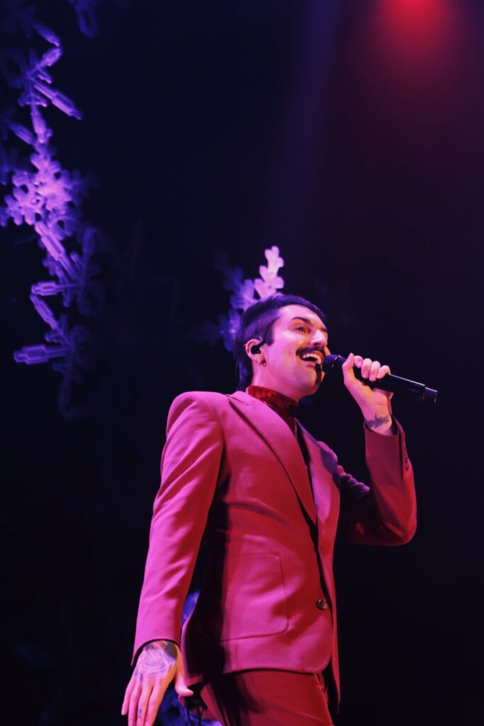 Mitch Grassi in a red suit singing on stage.