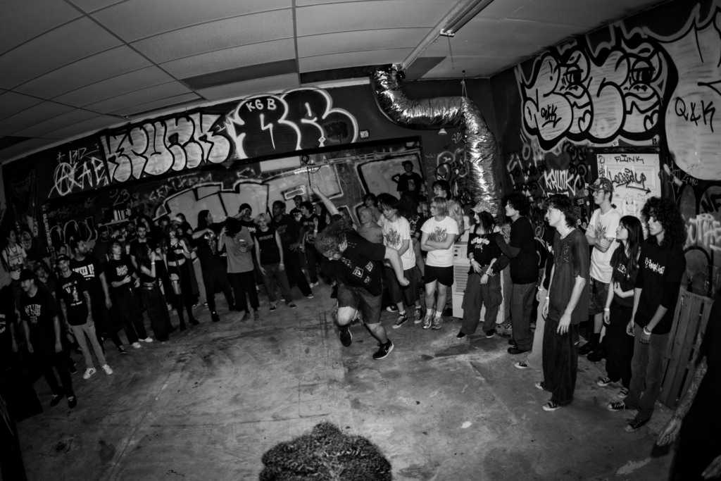 black and white photo of teenagers standing around as a young man dances