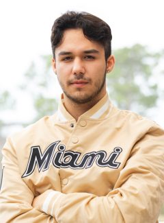 Man with dark brown hair wearing a yellow jacket.